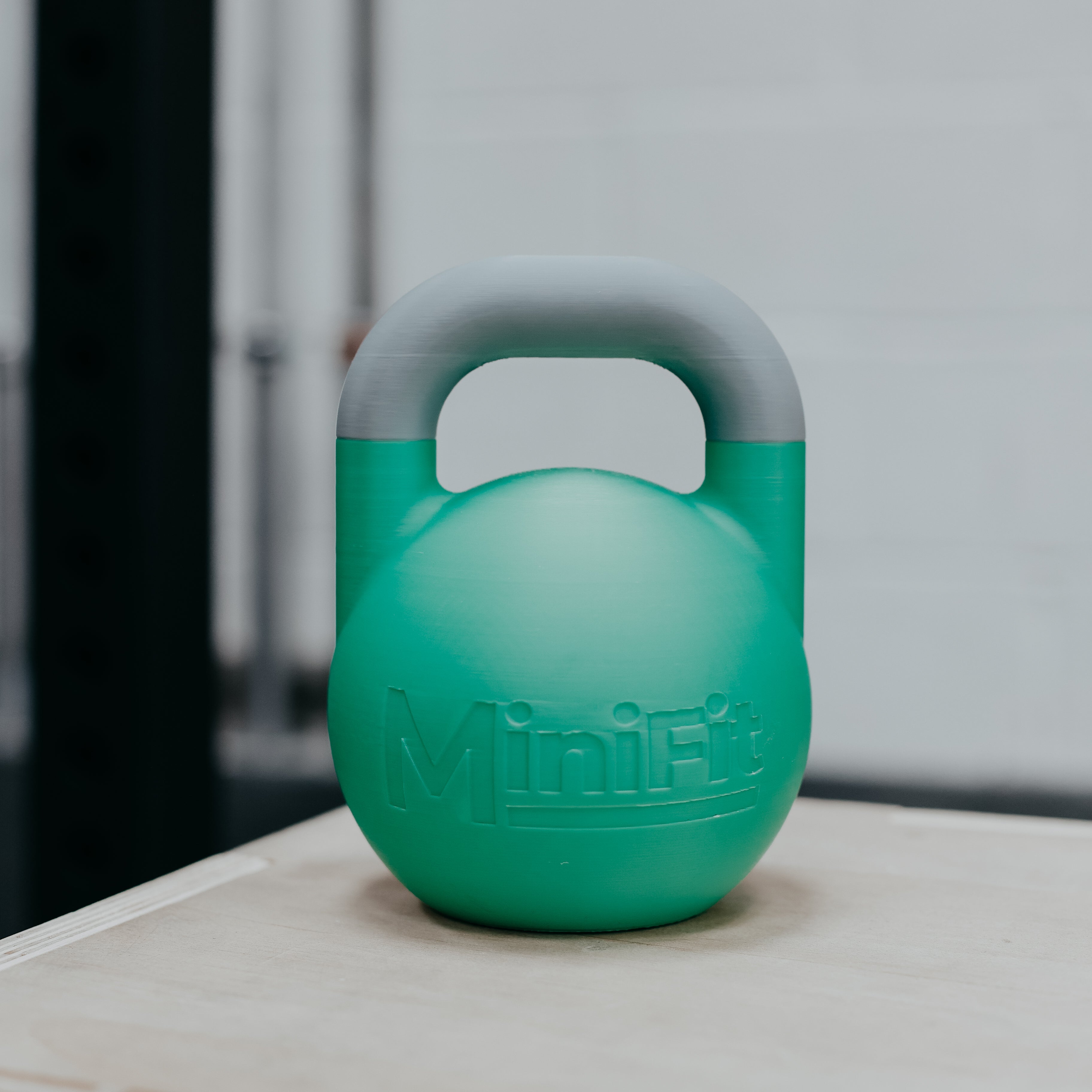 Green kids kettlebell with grey handle on a white surface