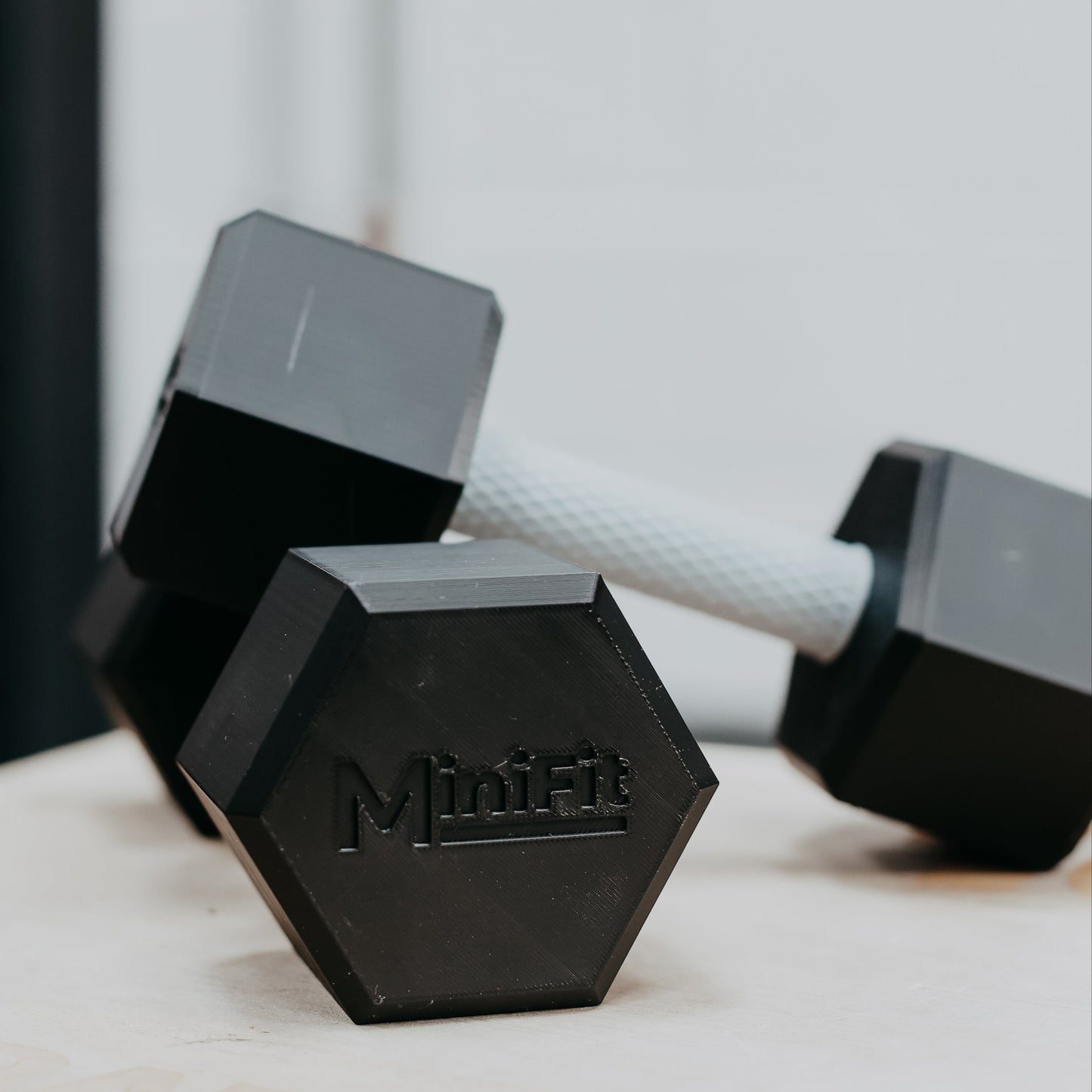 Pair of black hexagonal kids dumbbells with MiniFit branding on a light surface.