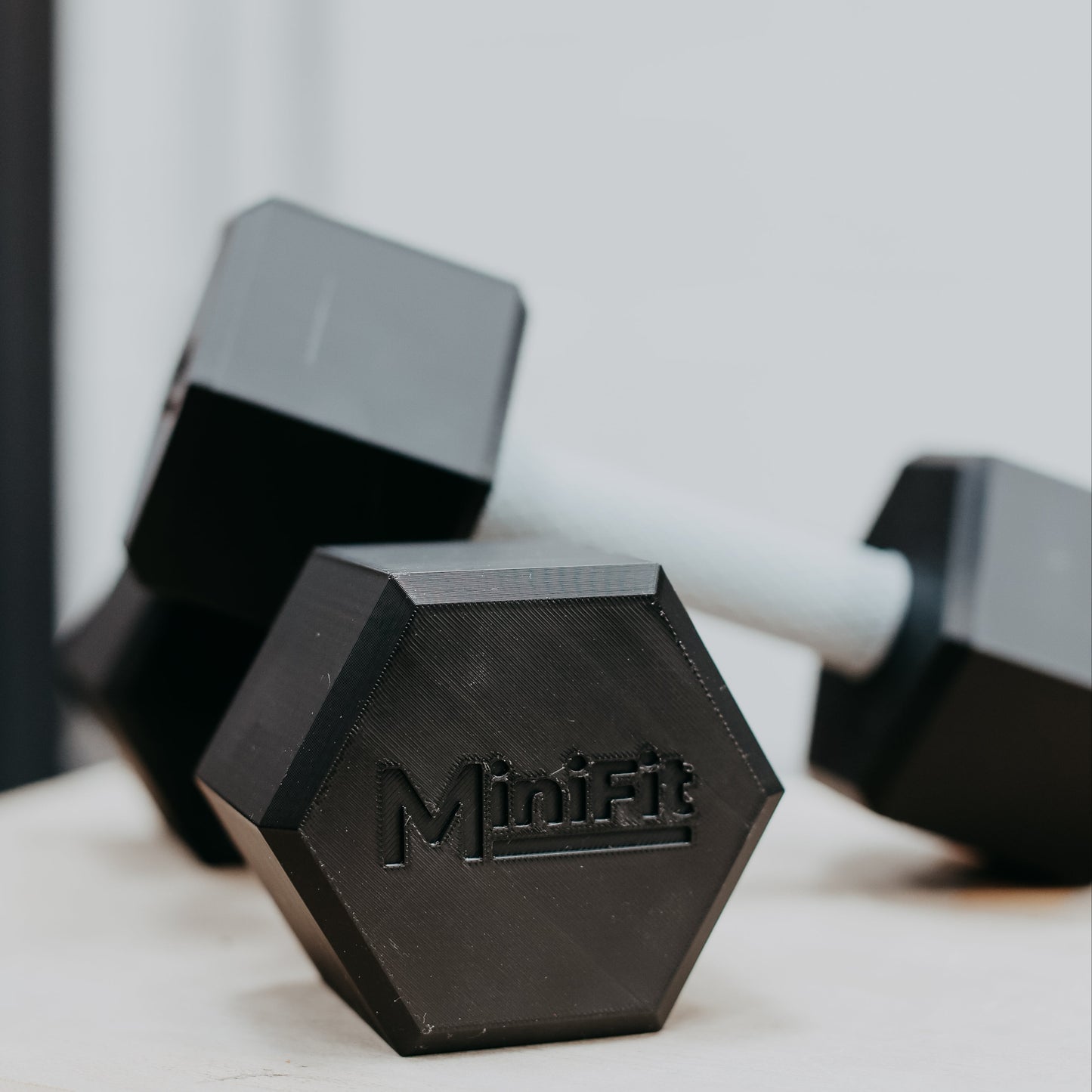 Pair of black kids dumbbells with Minifit branding on a light surface.