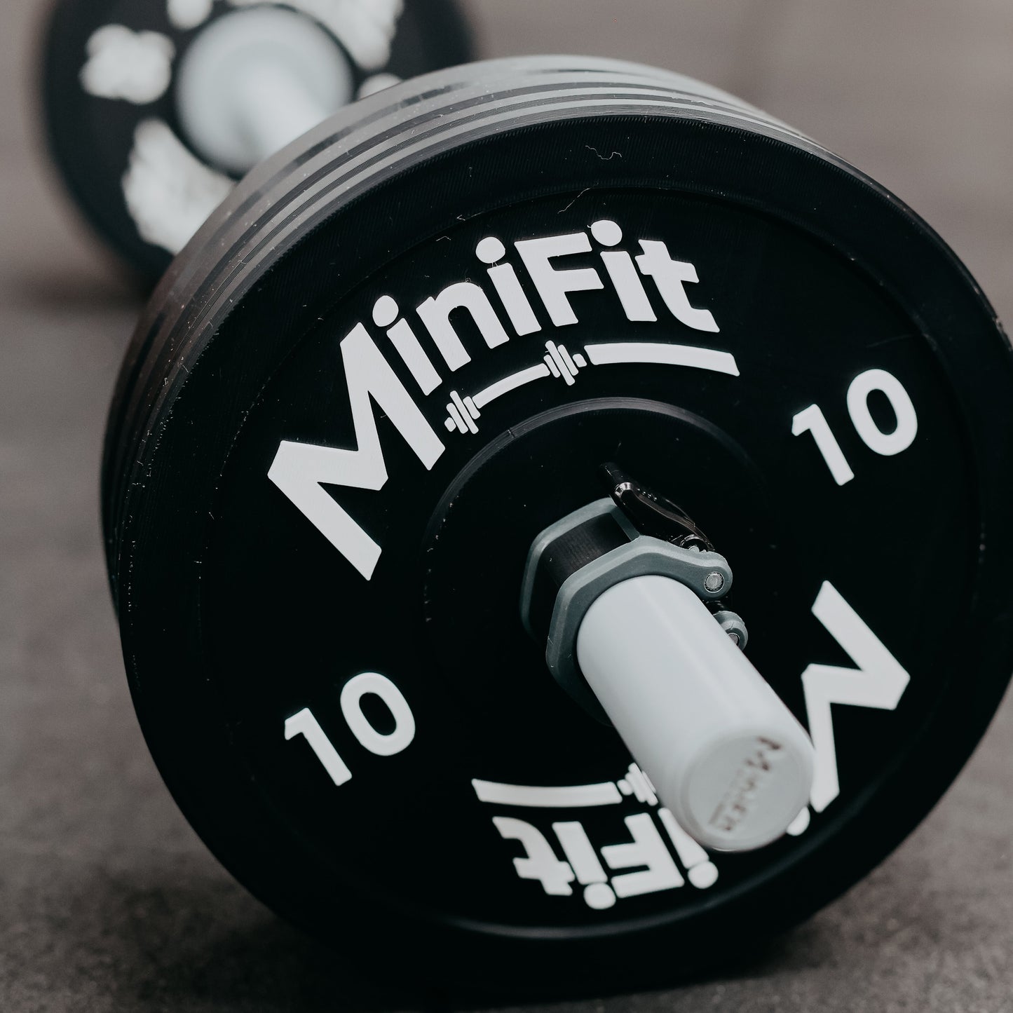 Black weight plate with 'MiniFit' branding on a gray surface