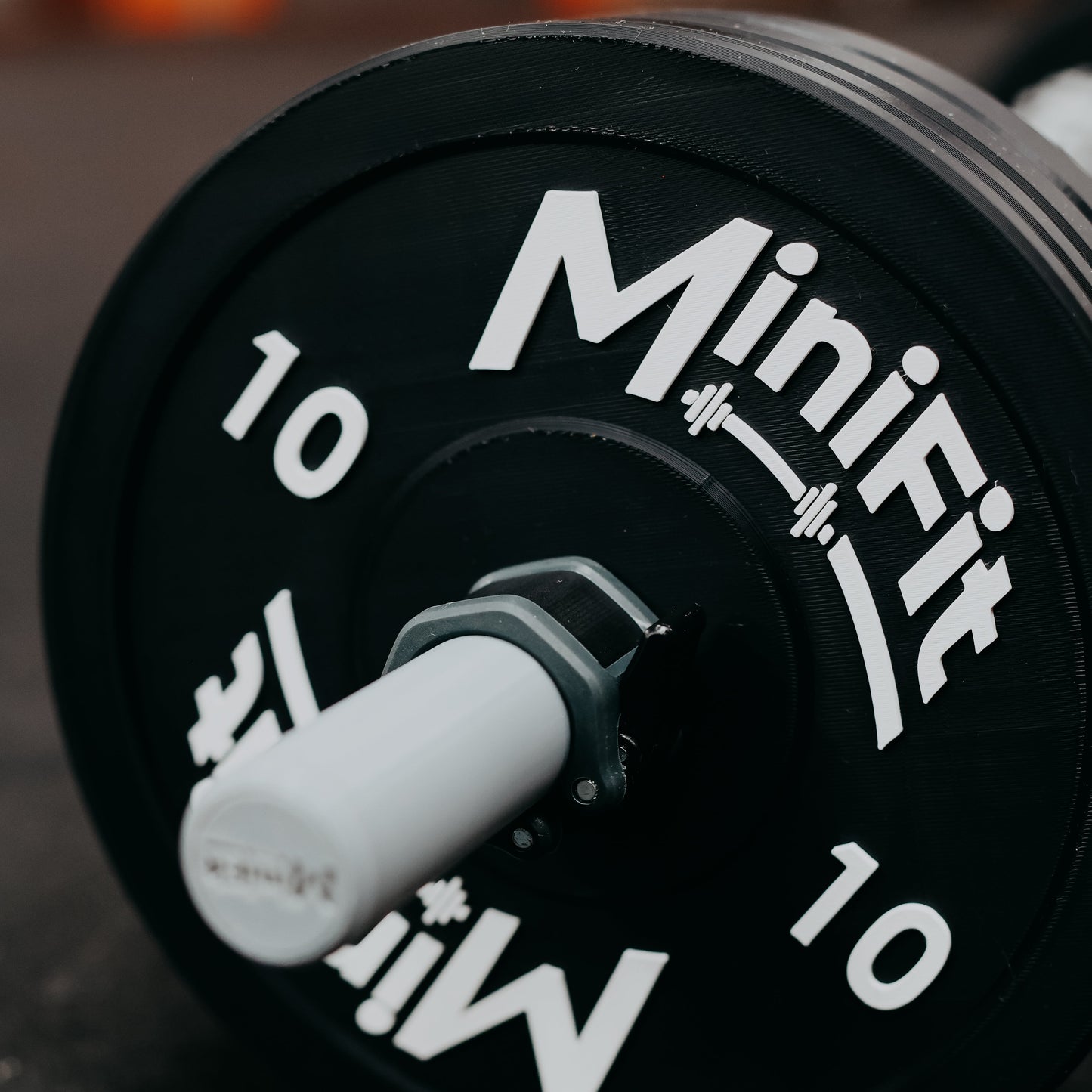 Black kids barbell set with 'Minifit' branding on a gym mats