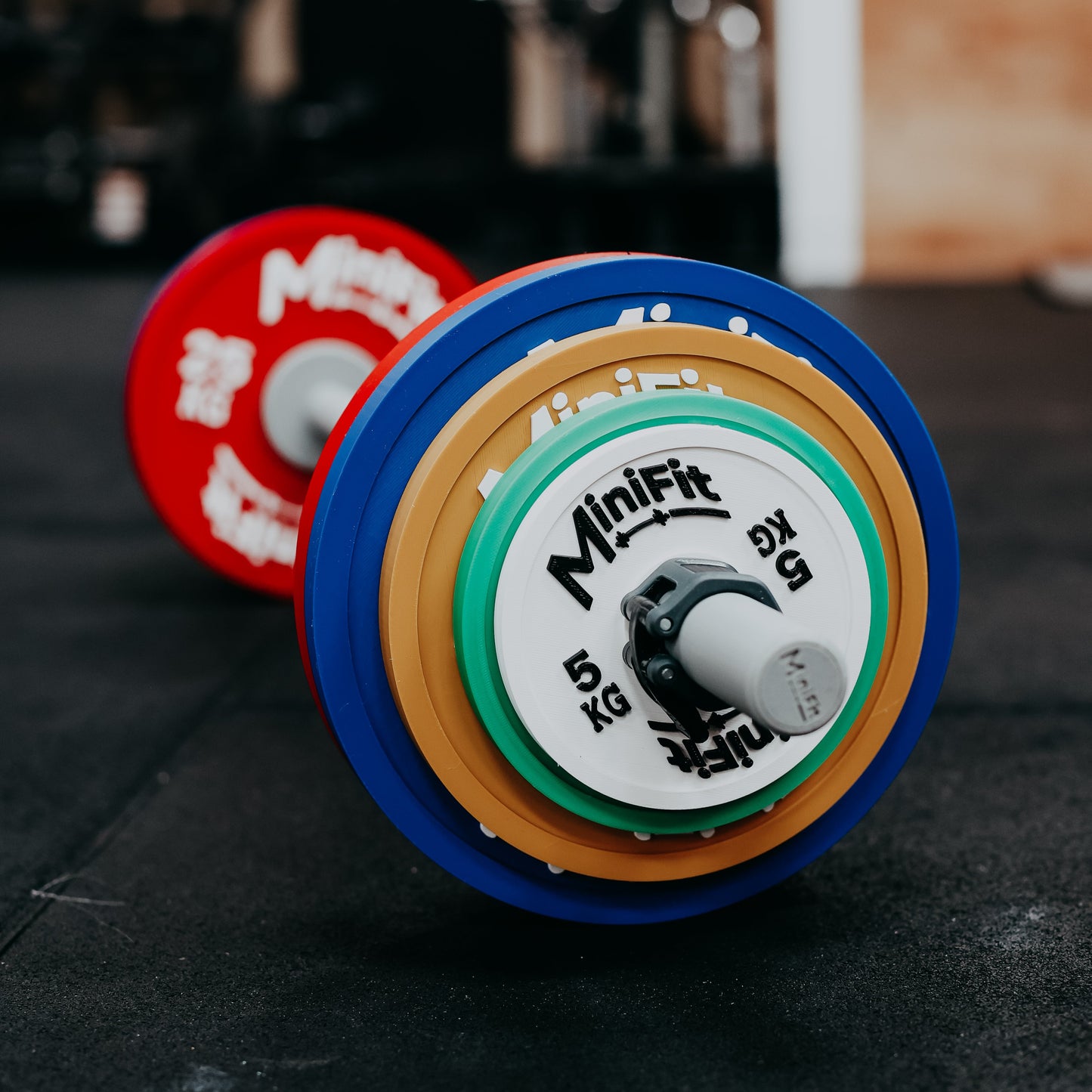 Kids barbell with colourful powerlifting weight plates on a gym background