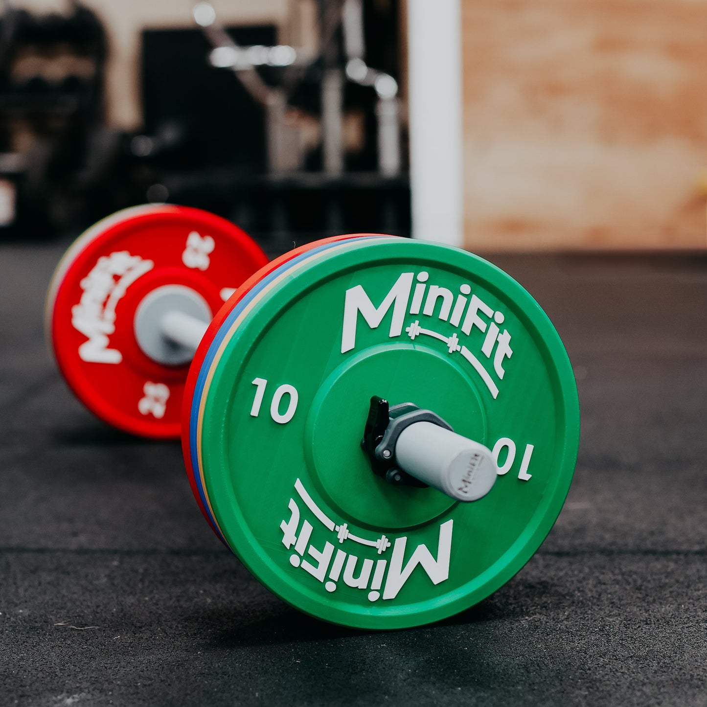 Children's bumper weight plates with Minifit branding on a gym floor.
