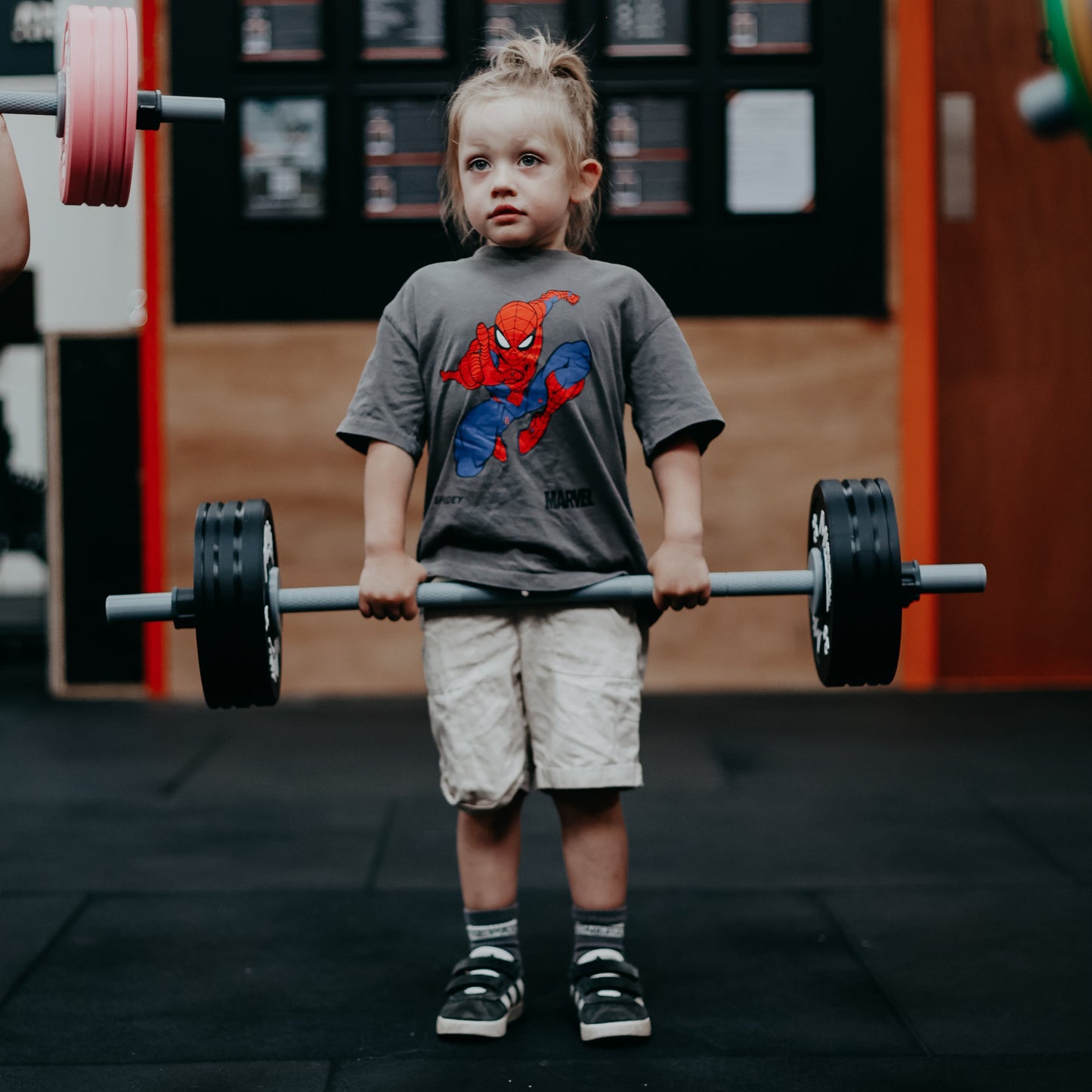 Two children lifting weights in a gym setting