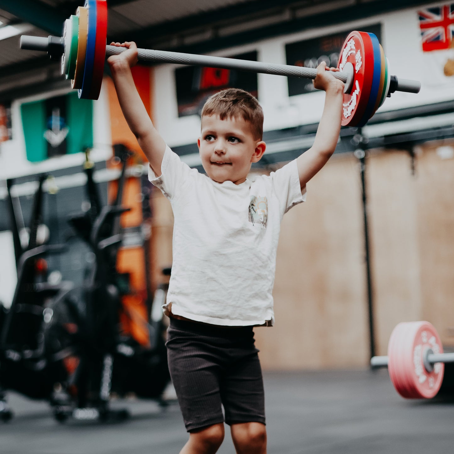 Child lifting MiniFit barbell weights in a gym setting