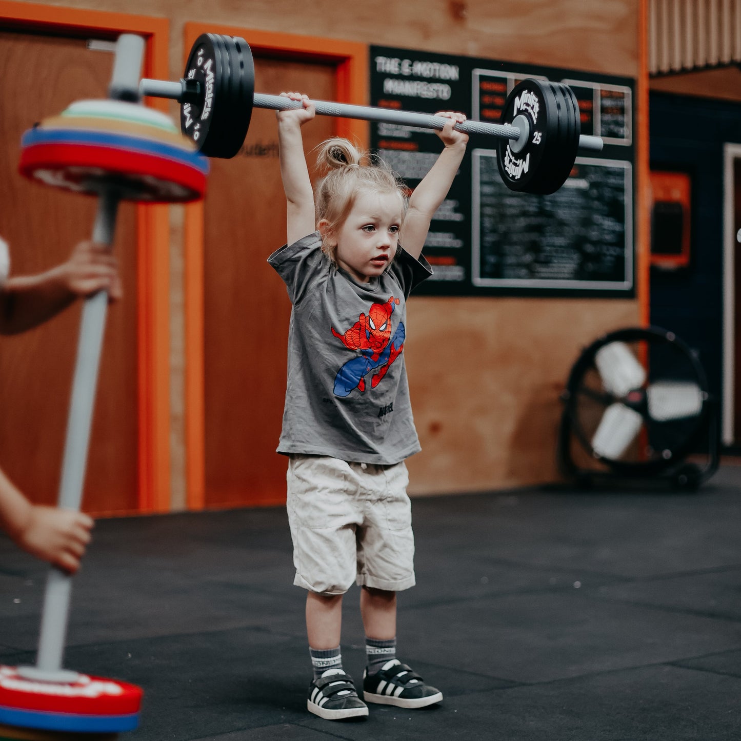 Child lifting a barbell in a gym setting