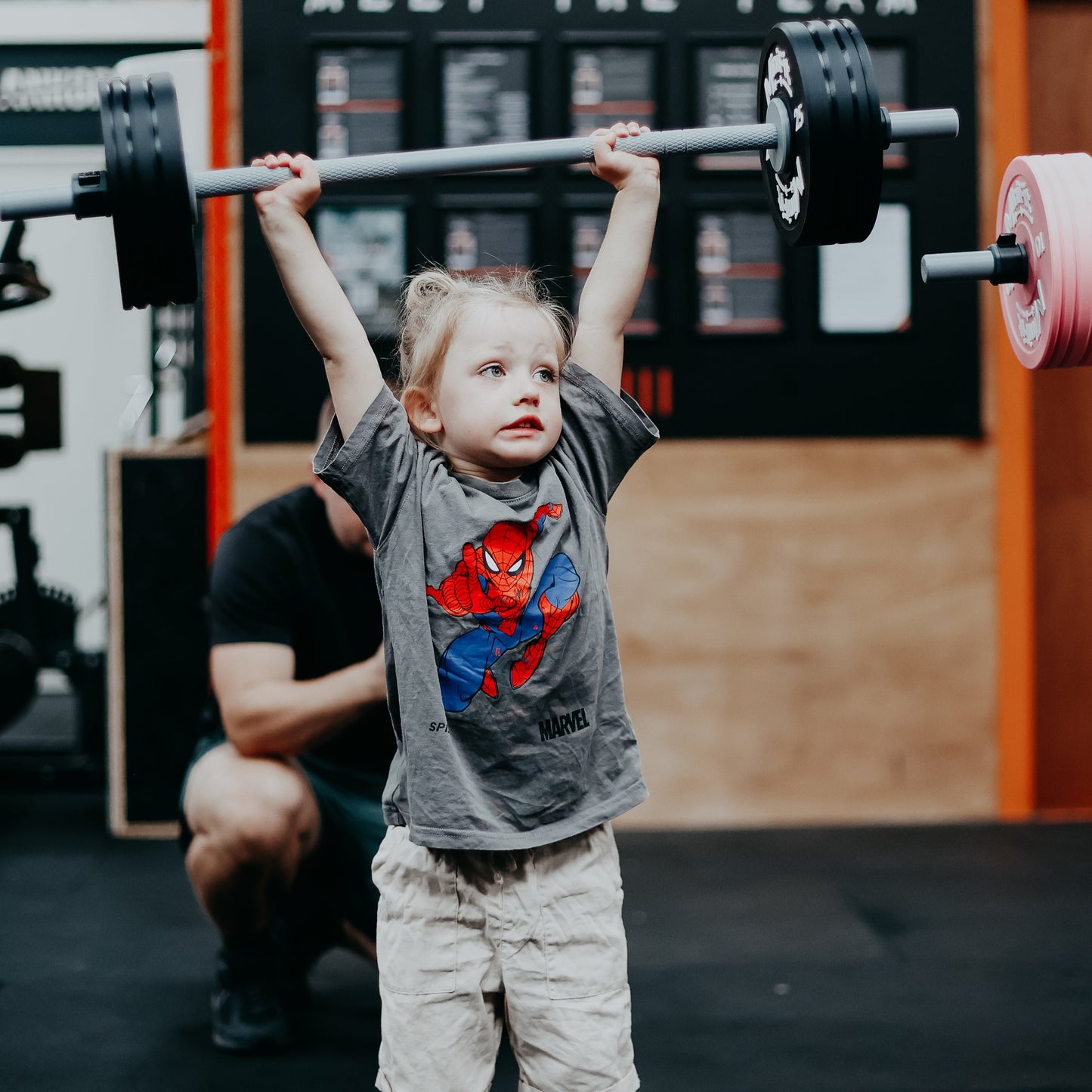 Child lifting a barbell in a gym setting