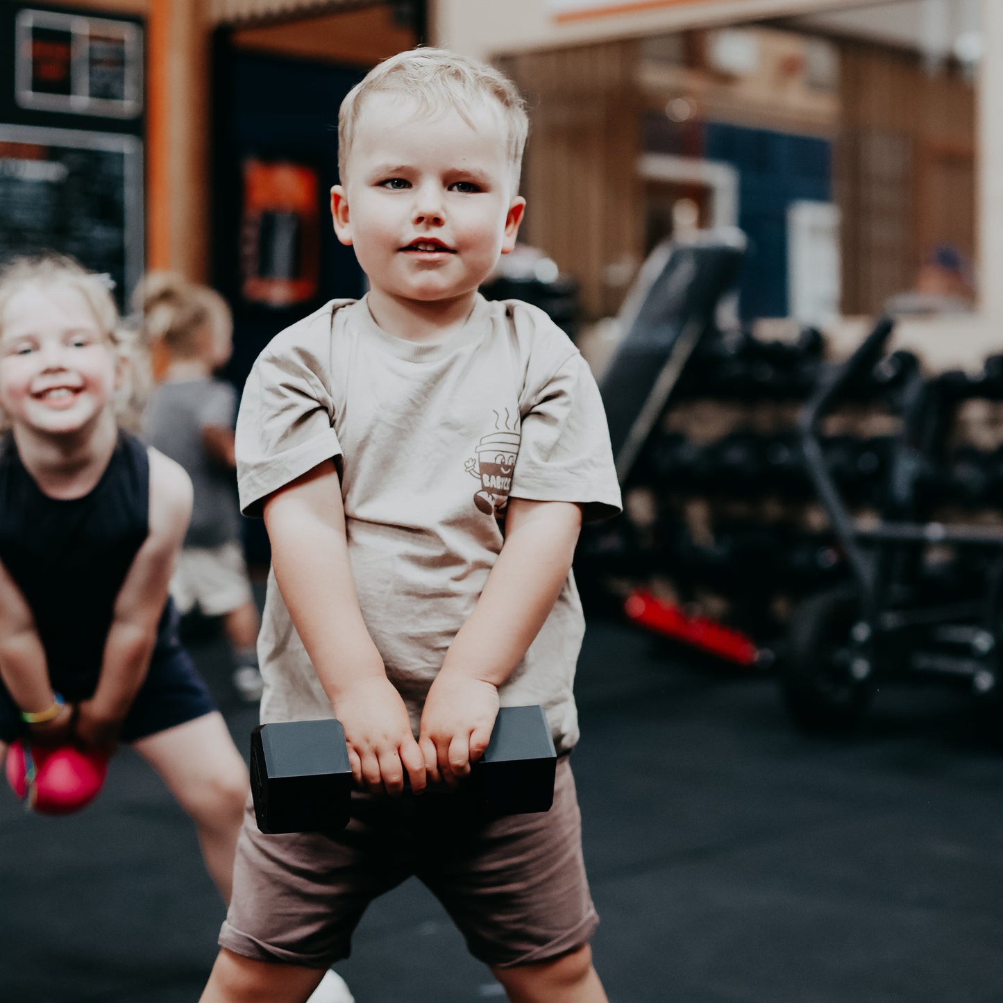 Child lifting dumbbels in a gym setting with blurred background