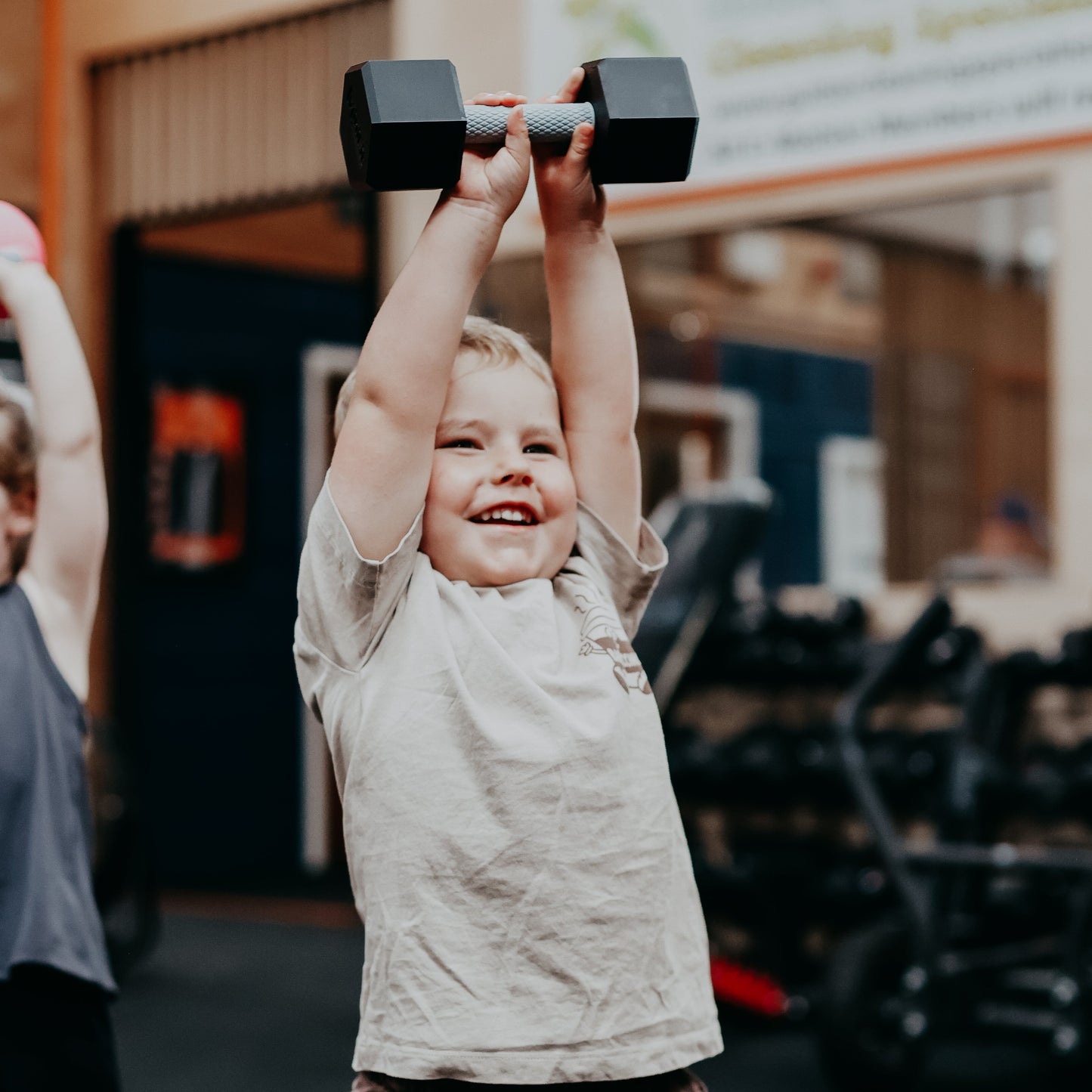Child lifting dumbbell weights in a gym setting