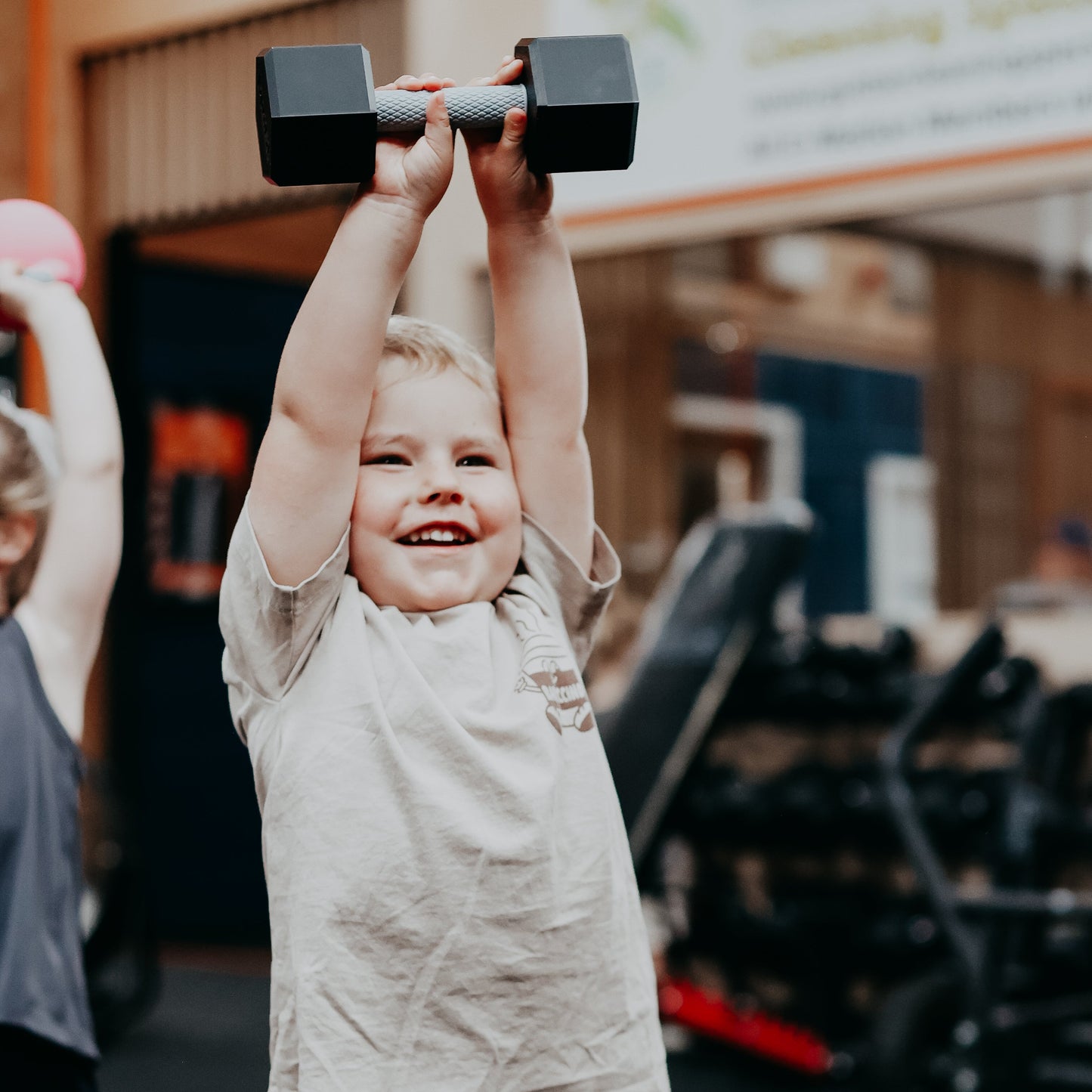 Child lifting dumbbell weights in a gym setting