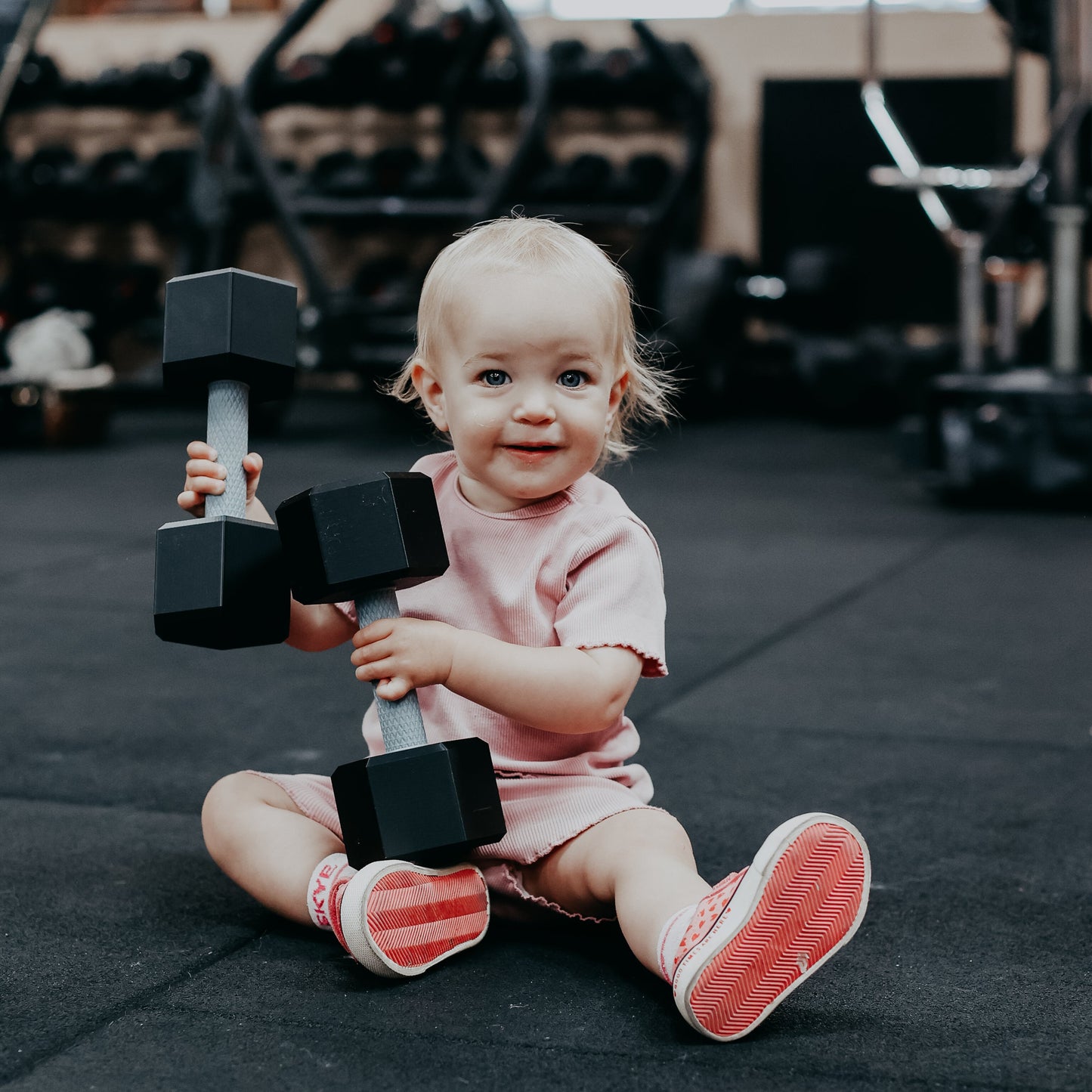 Child holding dumbbells in a gym setting