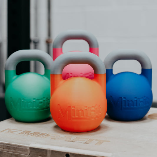 Four colorful children's kettlebells on a wooden surface with a blurred background