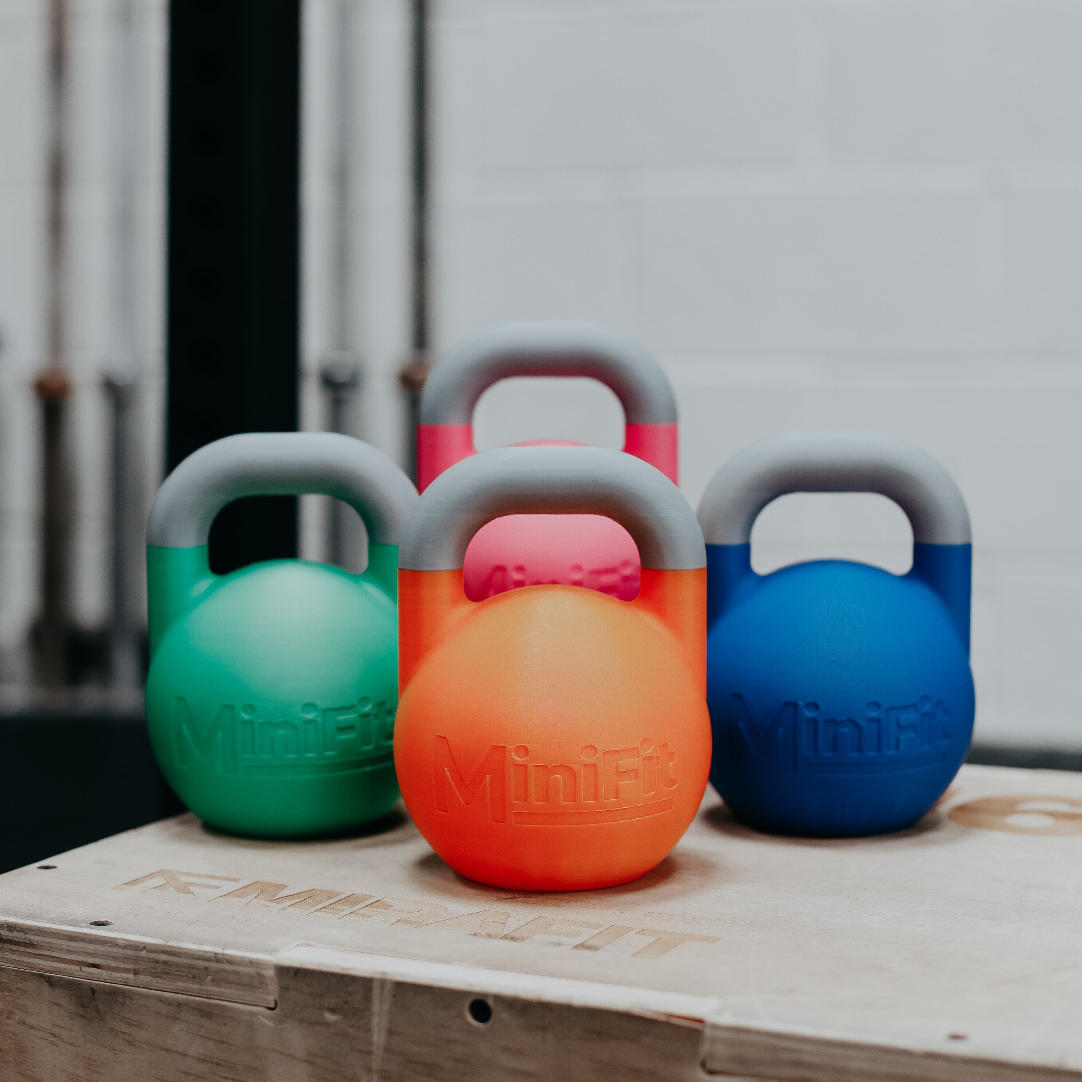 Colourful mini kids kettlebells on a wooden platform with a gym background