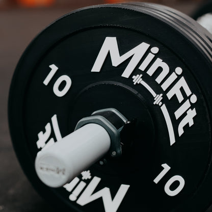 Black kids barbell set with 'Minifit' branding on a gym mats 