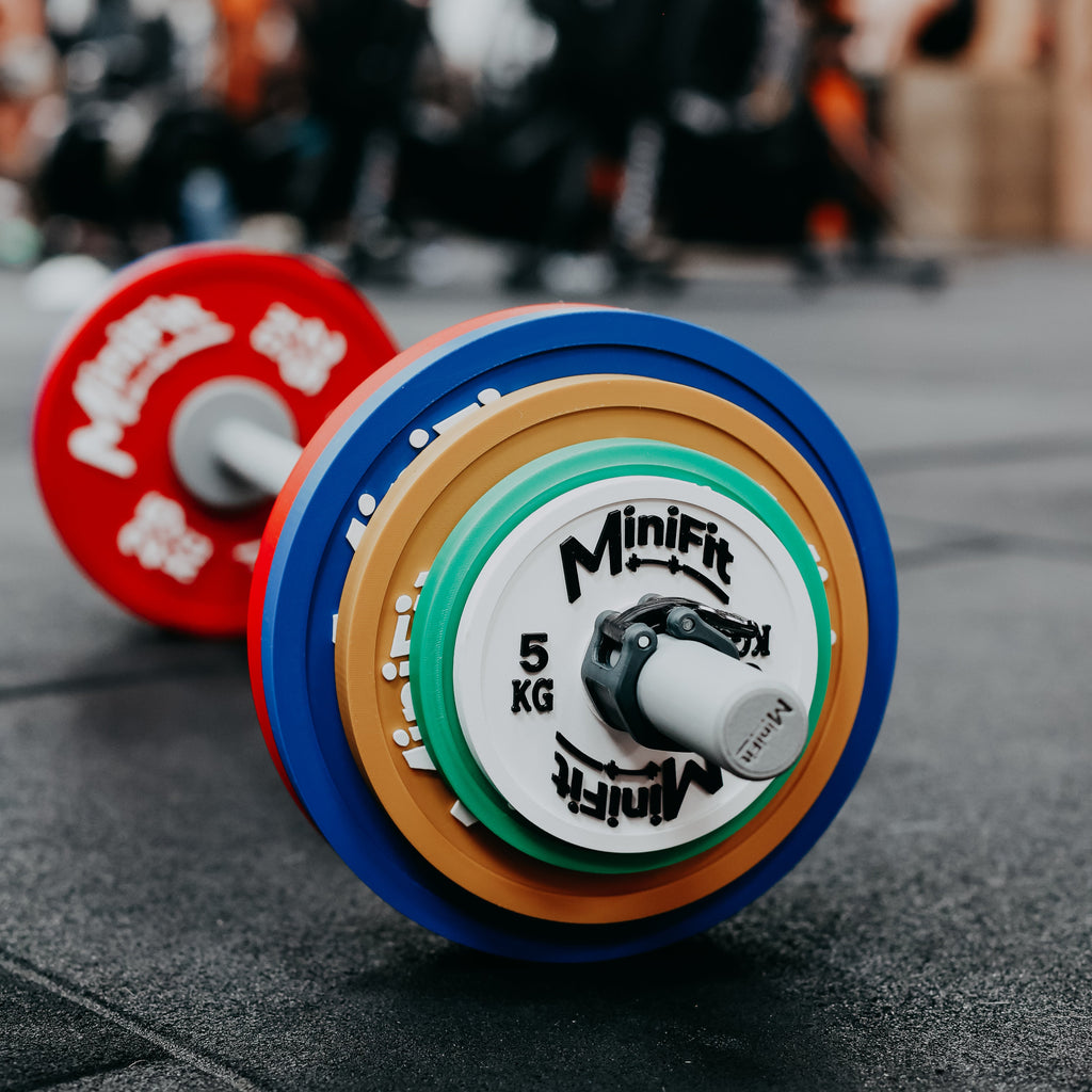 Colourful kids barbell with Minifit branding on a gym floor.