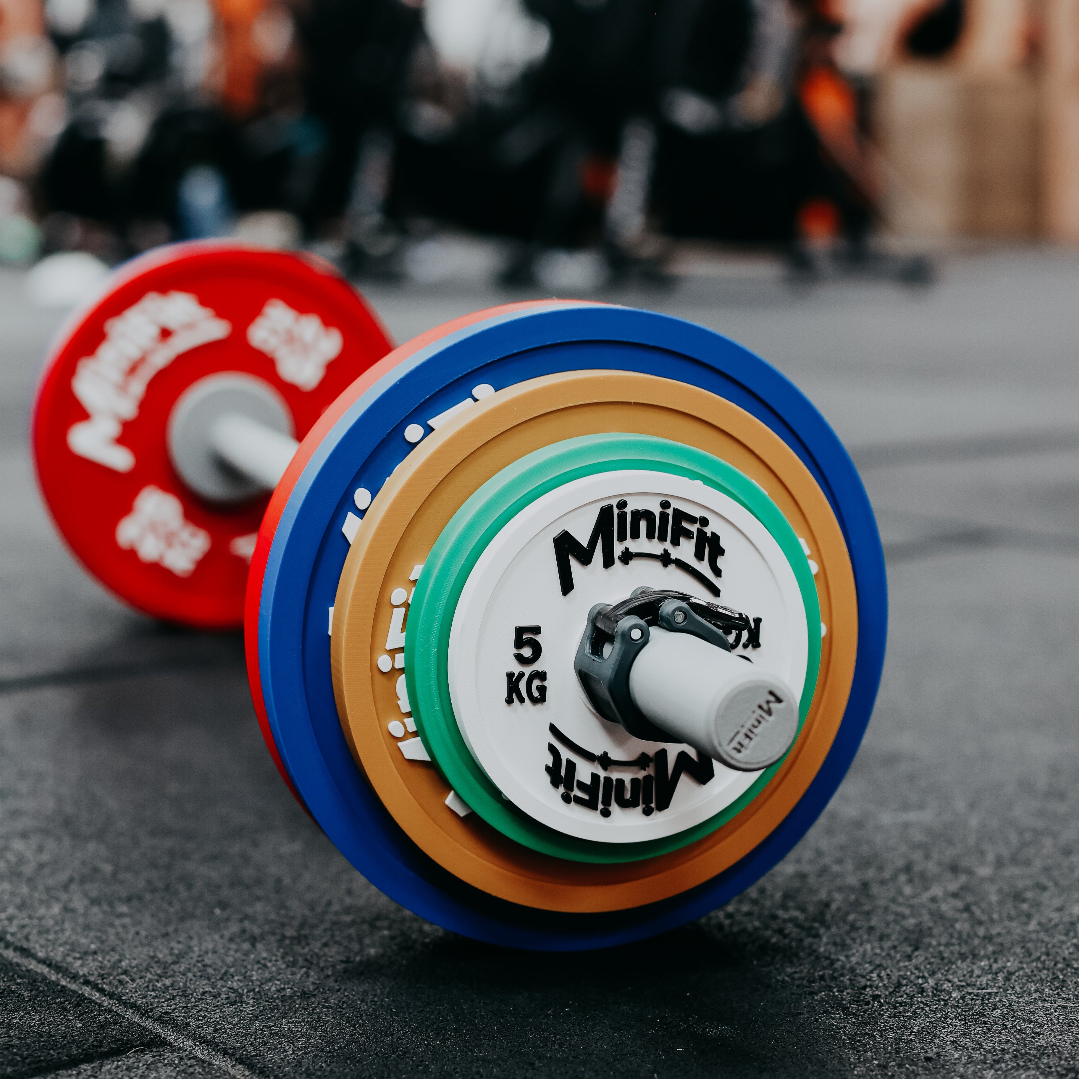 Colourful kids barbell with Minifit branding on a gym floor.