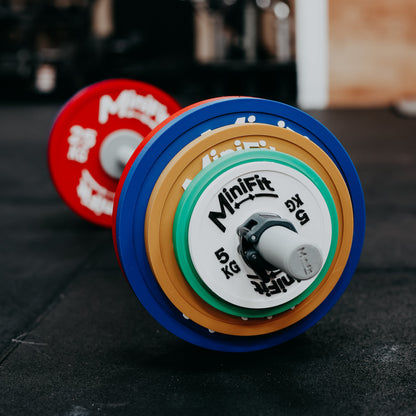 Kids barbell with colourful powerlifting  weight plates on a gym background