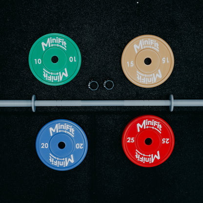 Set of Minifit kids weight plates with a bar on a black gym mat