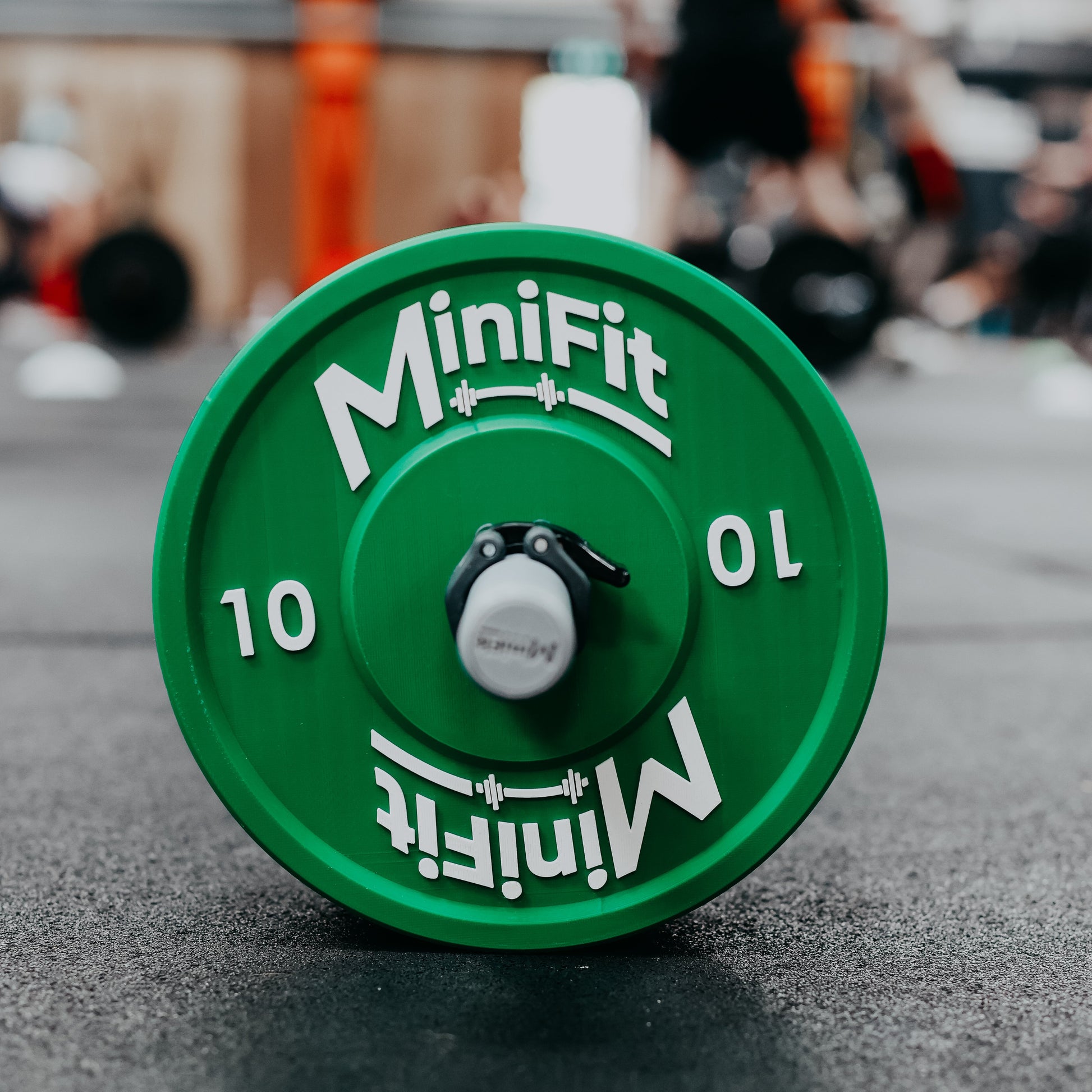 Green kids weight plate with Minifit branding on a gym floor.