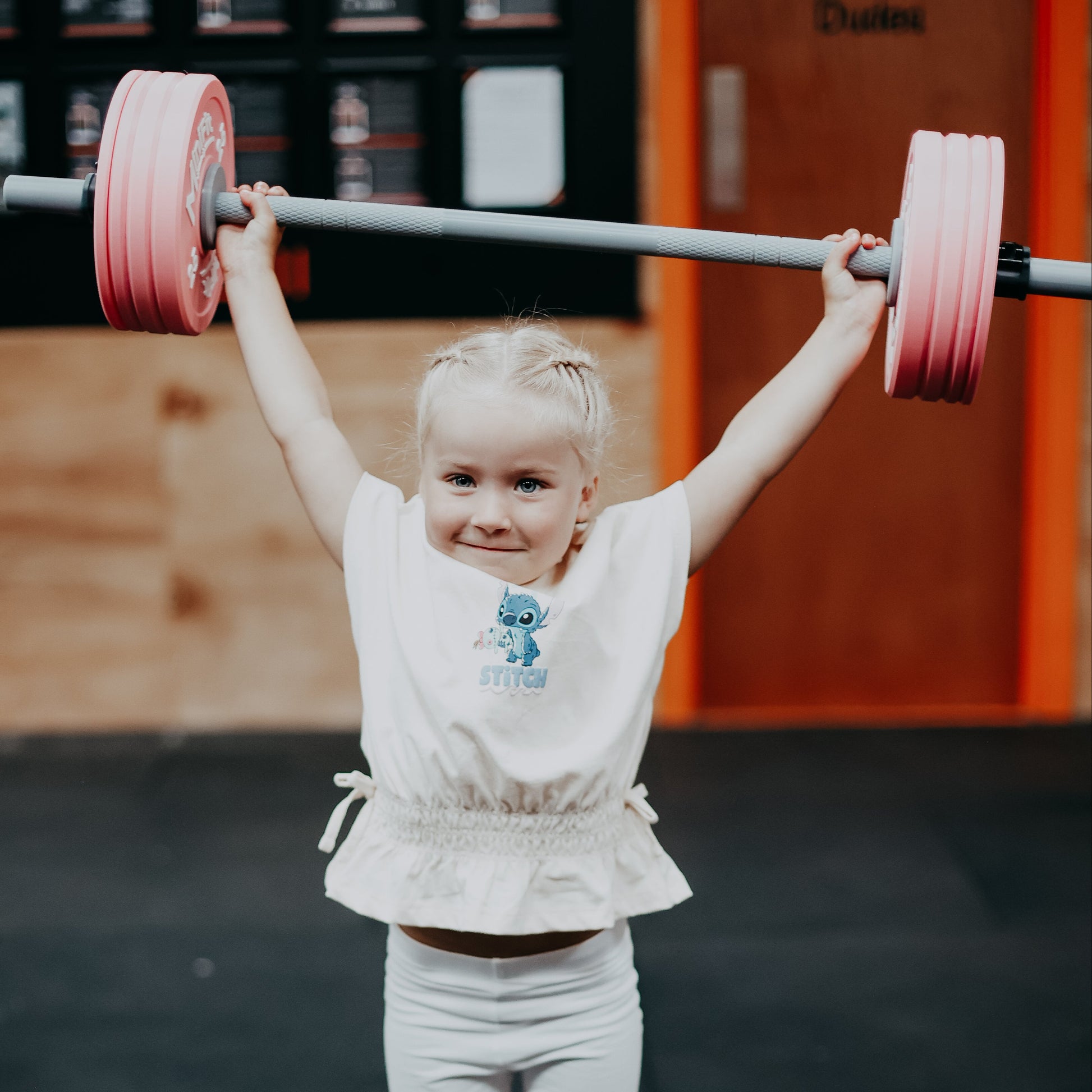 Child lifting a barbell in a gym setting