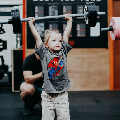 Child lifting a barbell in a gym setting 