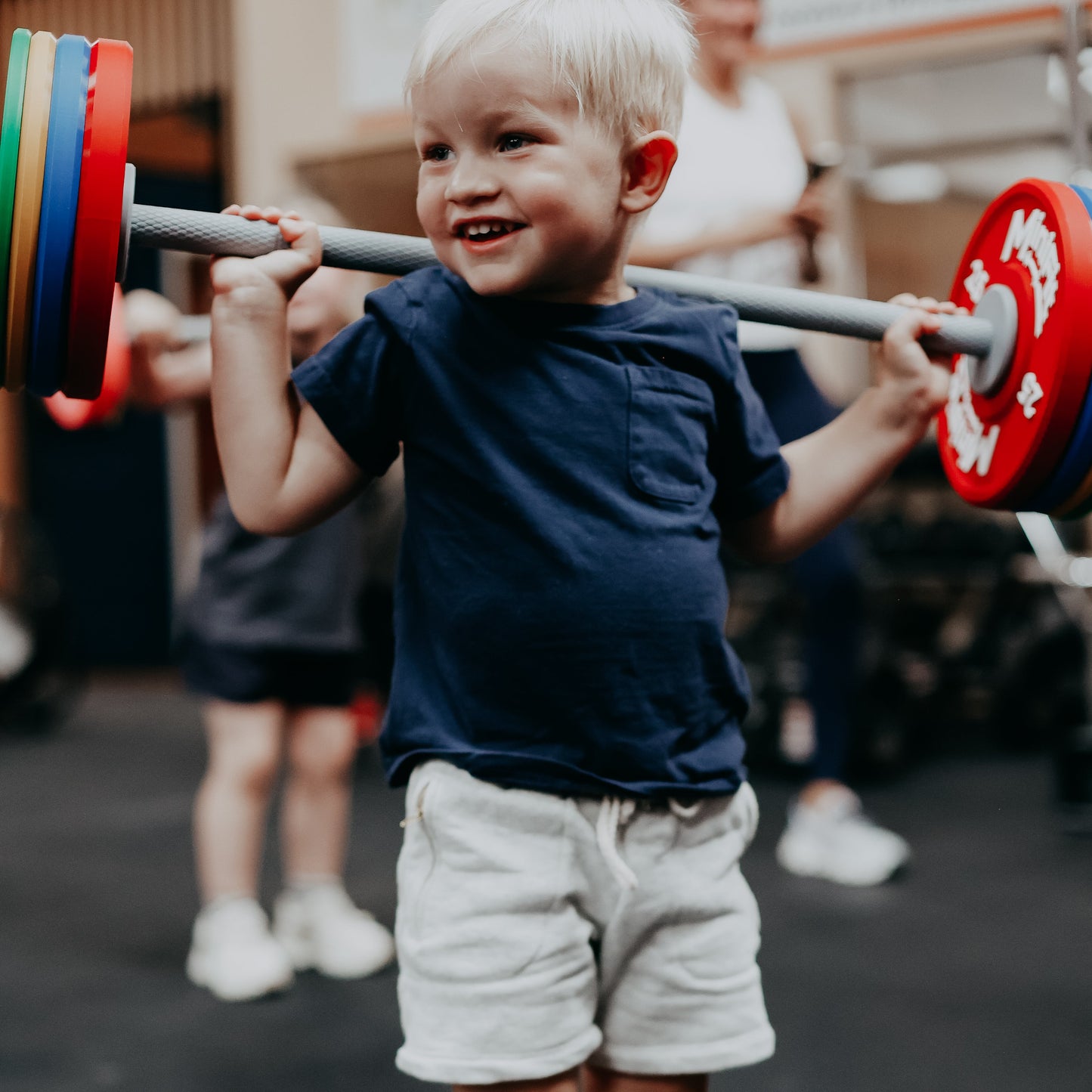 Child lifting a barbell with weights in an indoor setting