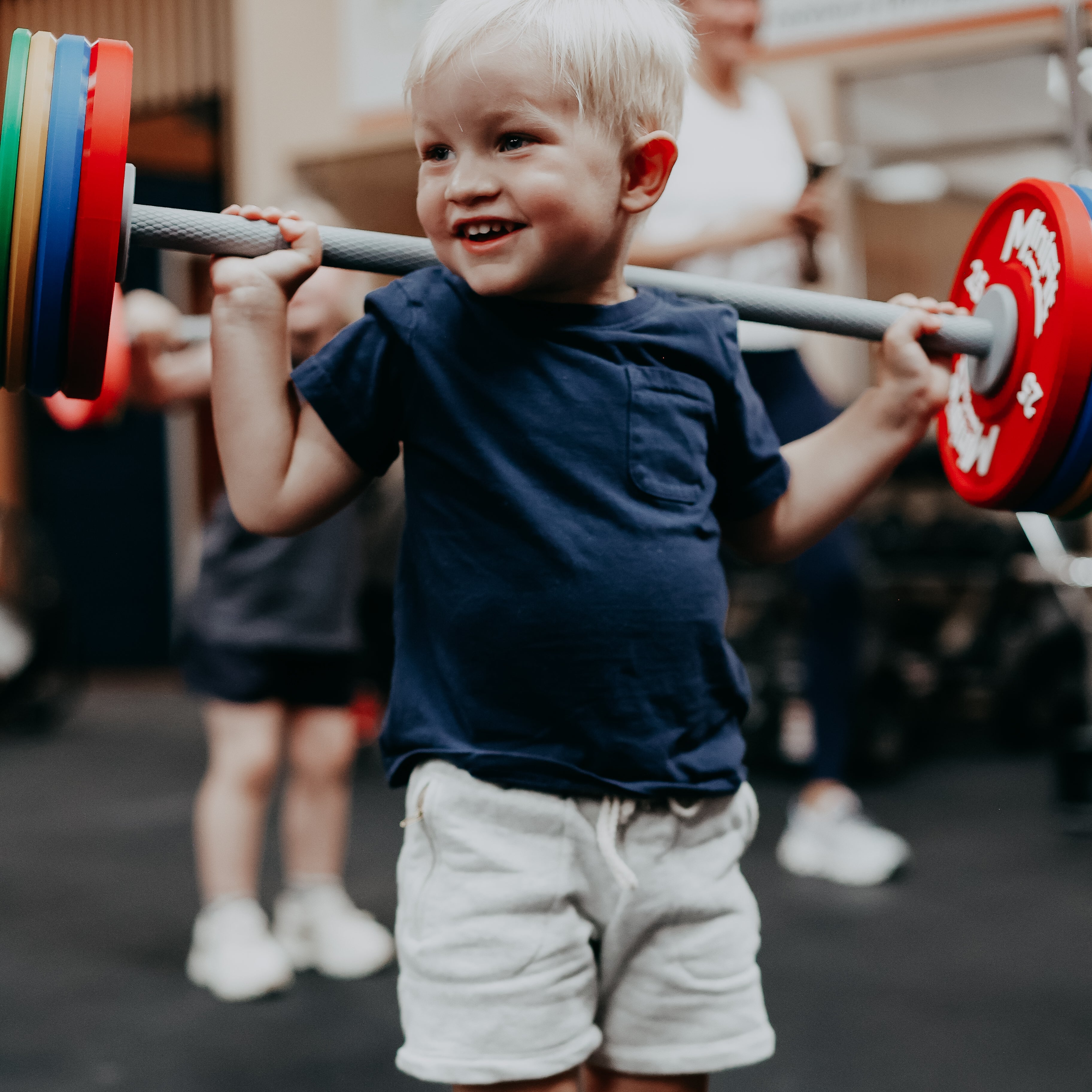 Child lifting a barbell with weights in an indoor setting