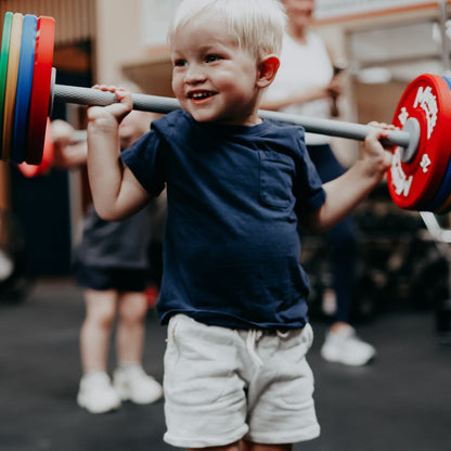 Child lifting a barbell with weights in an indoor setting