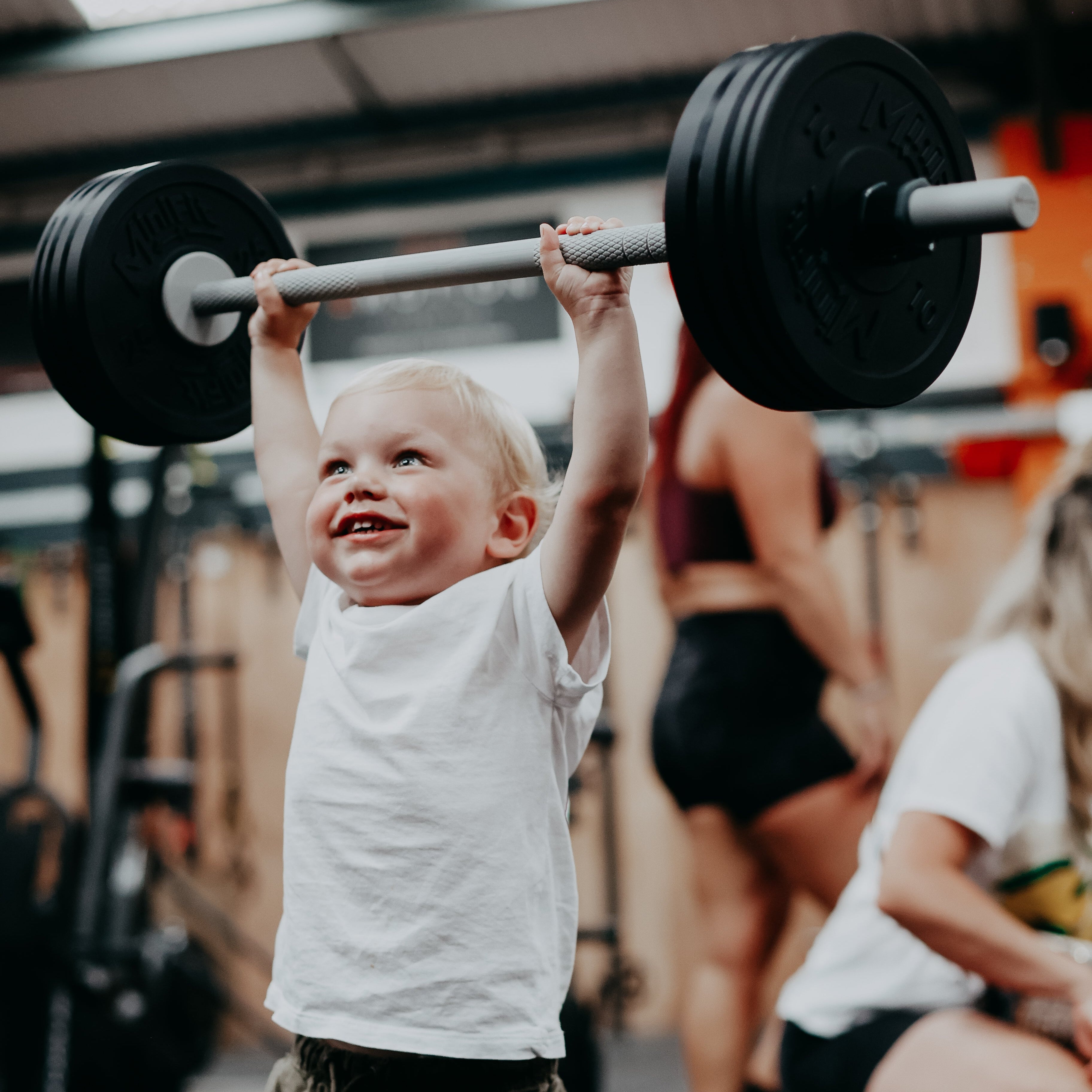 Child lifting a barbell in a gym setting