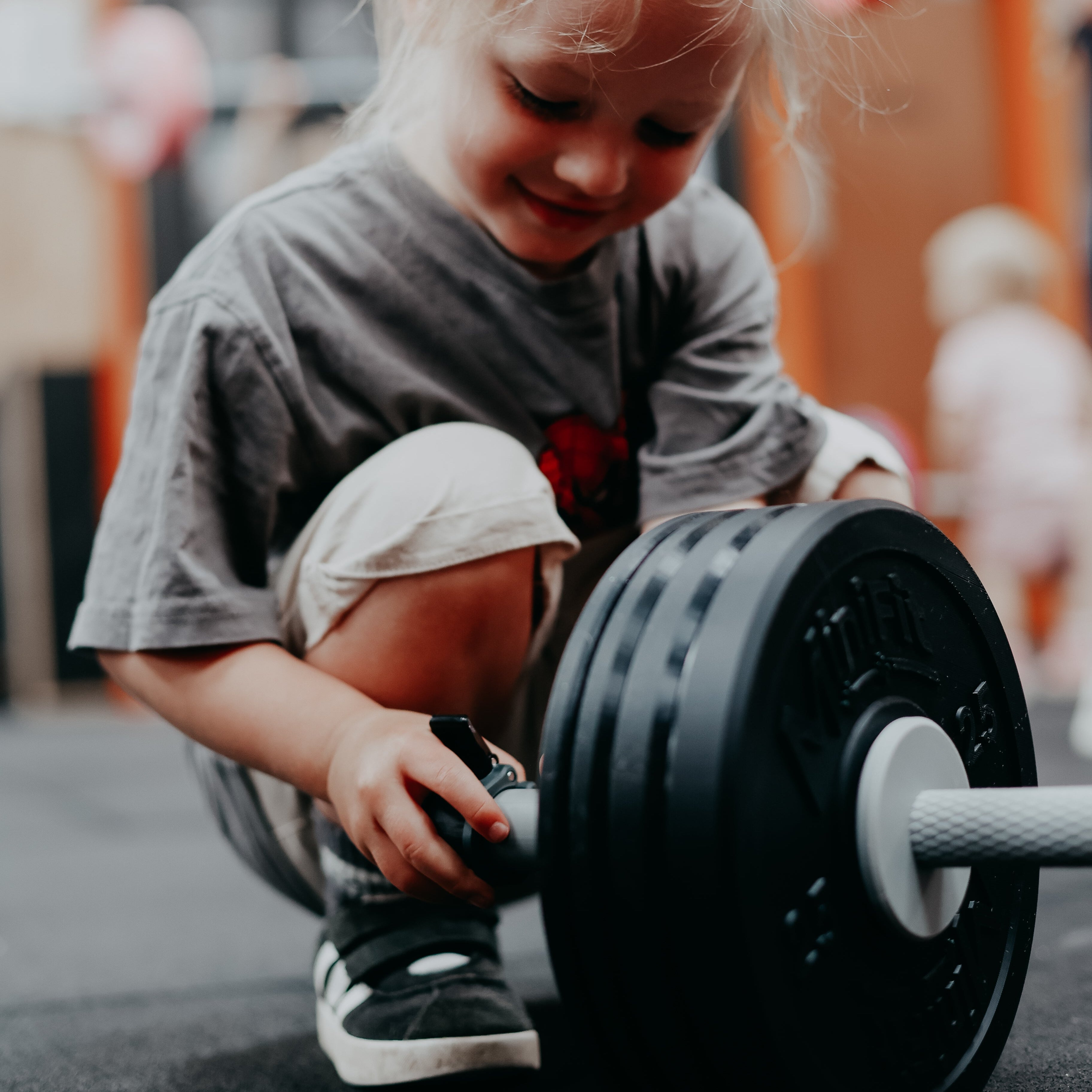 Child playing with a barbell in an indoor setting