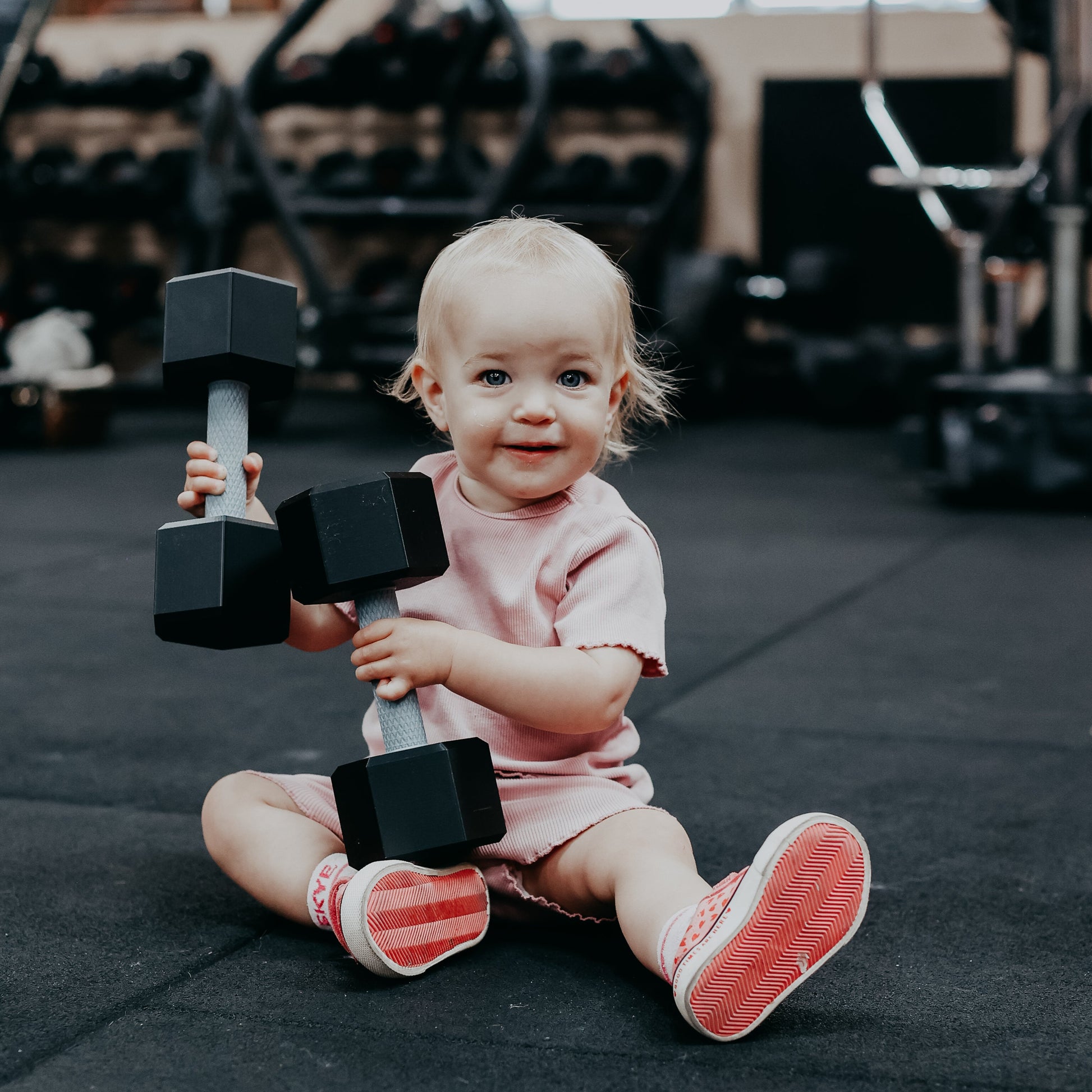 Child holding dumbbells in a gym setting